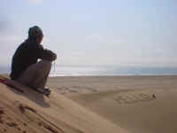 Hello! Anand sits atop a dune by the coast.
